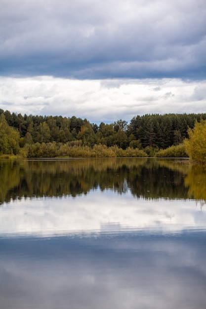 Reflexões de árvore de folhagem colorida na água calma da lagoa em um lindo dia de outono. Um lugar tranquilo e bonito para relaxar.