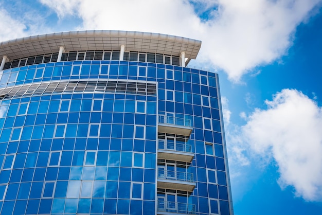 Reflexões do céu azul e das nuvens do prédio de escritórios nas janelas