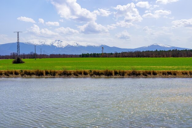 Reflexões do sol na água do lago azul em uma paisagem verde com montanhas nevadas