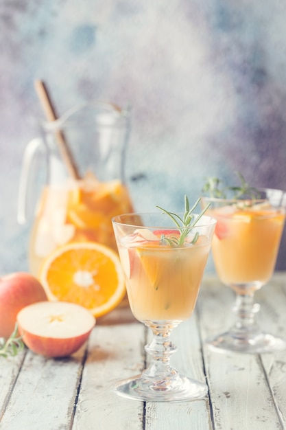 Refrescante bebida de verão sangria ou ponche com frutas em um copo e pincher sobre madeira