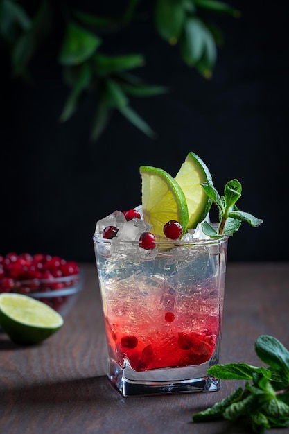 Refrescante bebida fría de limonada hecha de arándano en vaso con cubitos de hielo, lima y hojas de menta