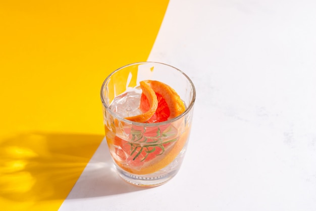 Refrescante bebida fría de verano en un vaso con una rodaja de pomelo y cubitos de hielo