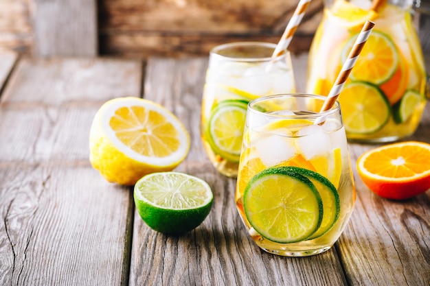 Una refrescante bebida helada de verano Sangría de vino blanco en vaso con lima, limón y naranja sobre un fondo rústico de madera