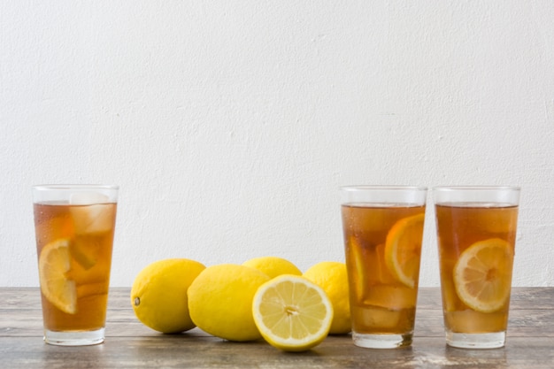 Refrescante chá gelado em vidro com limão na mesa de madeira