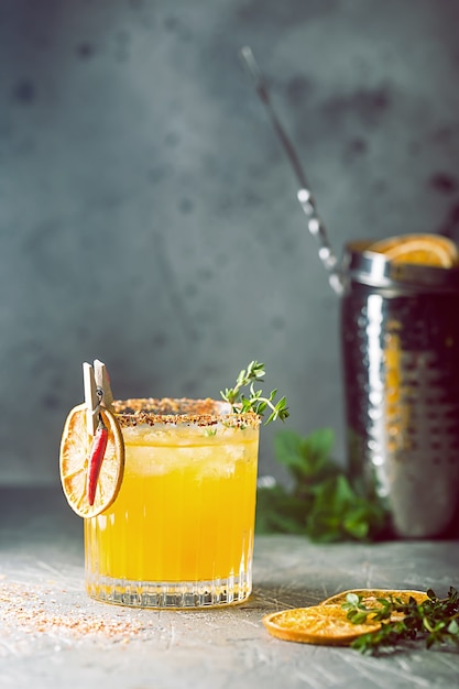 Refrescante cóctel de cítricos de verano con naranja, jugo de limón y hielo en un vaso sobre una superficie gris