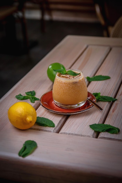 Refrescante cóctel de gin tonic alcohólico con batido de melocotón y menta con cubitos de hielo en la terraza de verano del restaurante Peach Fizz