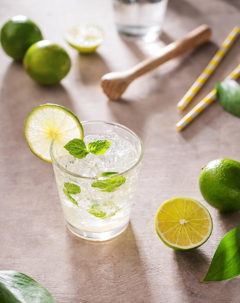 Refrescante cóctel mojito con menta y lima en un vaso con hielo sobre fondo rosa con sombras matutinas Concepto bebida cítrica de verano