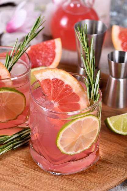 Refrescante cóctel orgánico con rodaja de pomelo, lima y ramita de romero en un vaso