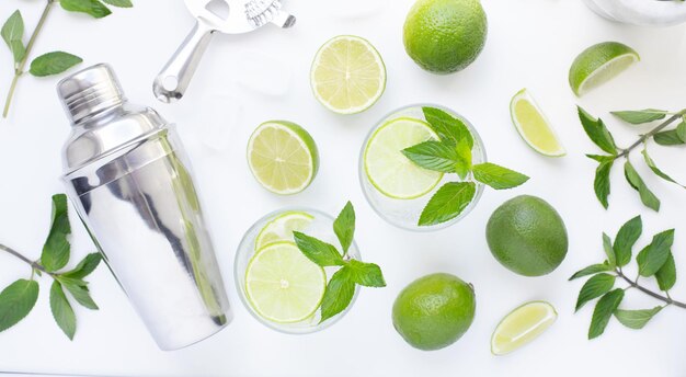 Refrescante coquetel de menta álcool mojito com rum e limão bebida gelada ou bebida com gelo suco de refrigerante shaker de água e utensílios de bar na mesa branca Vista superior Postura plana