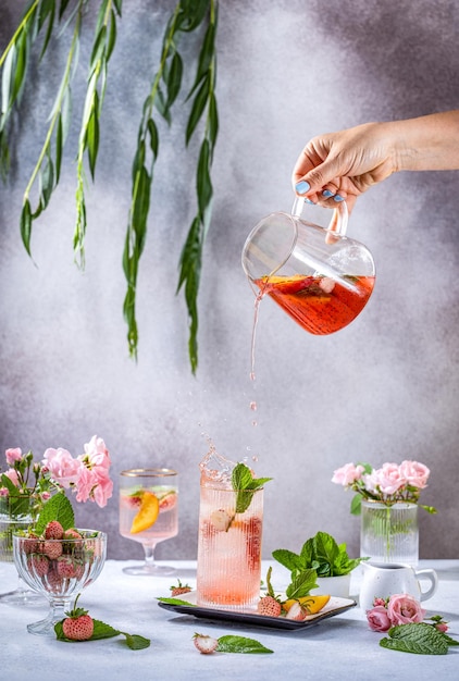 Refrescante limonada con melocotones, jarabe de arce, menta fresca y fresas de pino en vaso alto