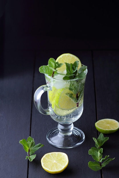 Refrescante mojito frío en un vaso alto con hielo menta limón y lima sobre un fondo negro Primer plano