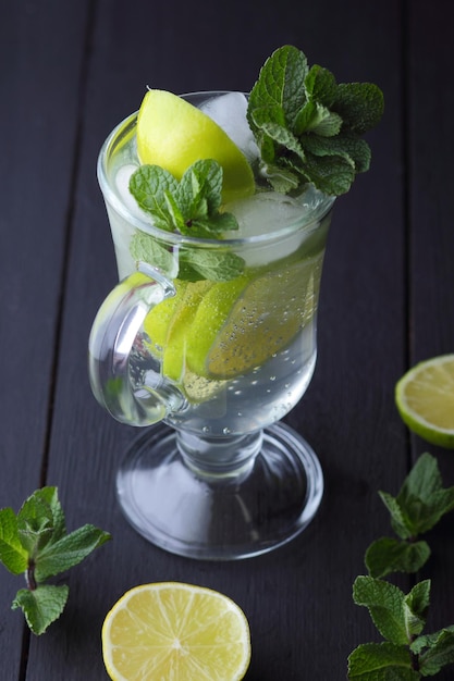 Refrescante mojito frío en un vaso alto con hielo menta limón y lima sobre un fondo negro Primer plano