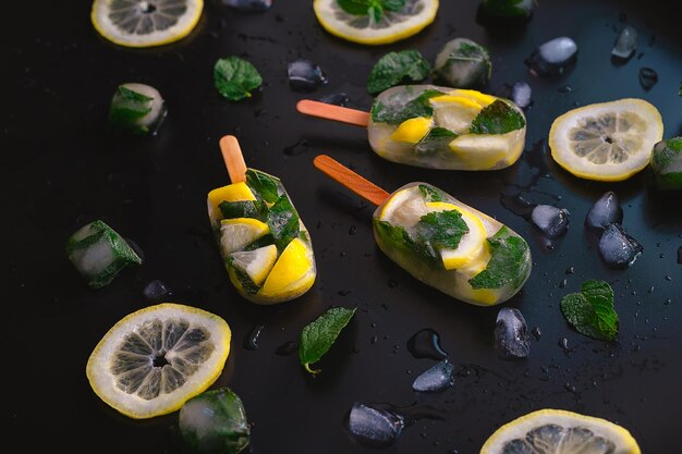 Foto refrescante picolé de frutas com limão e hortelã em fundo escuro