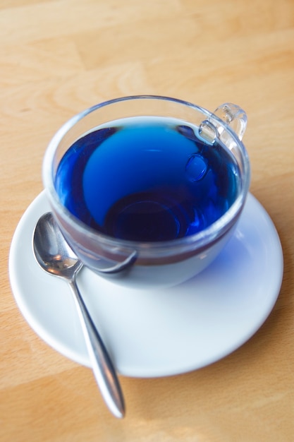Refrescante té chino azul en una taza transparente sobre una mesa de madera