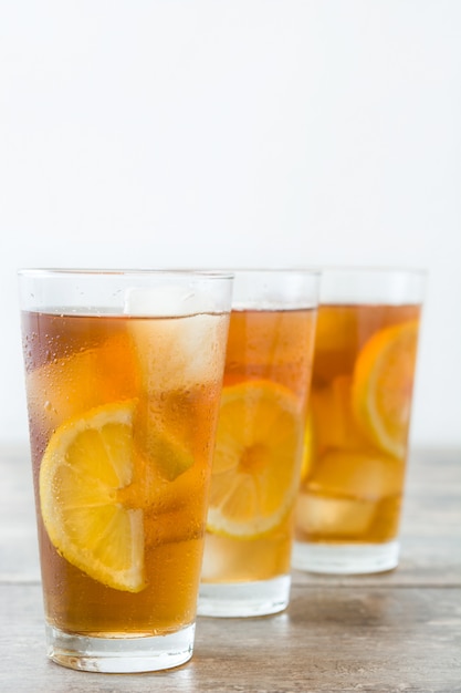 Refrescante té helado en vaso con limón en la mesa de madera