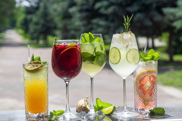 Refrescantes cocktails de verão com uma fatia de limão. Bebida alcoólica. Decorado com um raminho de hortelã, frutas cítricas e cubos de gelo. No bar.