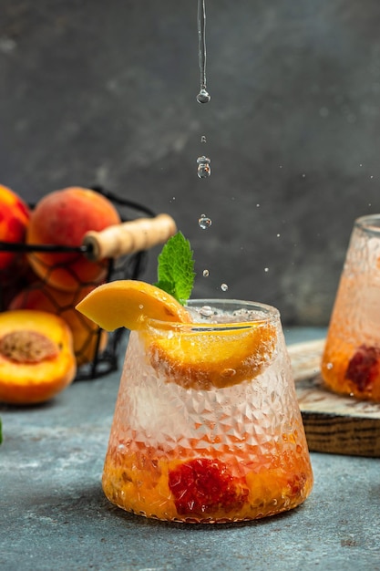 Refrescantes cócteles sin alcohol caseros de verano bebidas cóctel de melocotón con cubitos de hielo y menta en vaso Gotas de salpicaduras de movimiento congelado