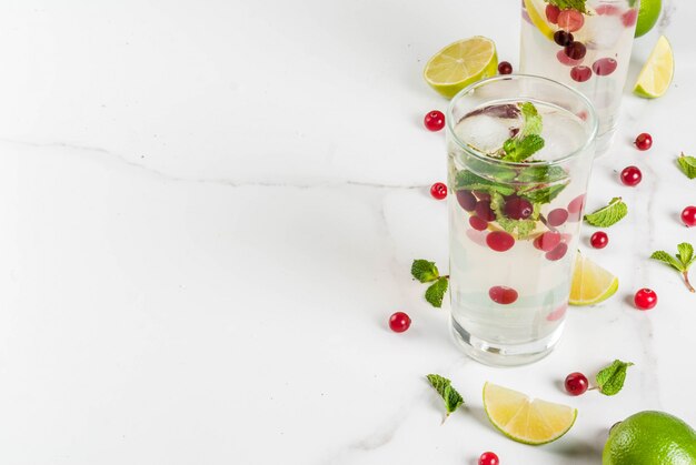 Refresco de outono e inverno beber mojito cranberry cocktail com limão e hortelã na mesa branca