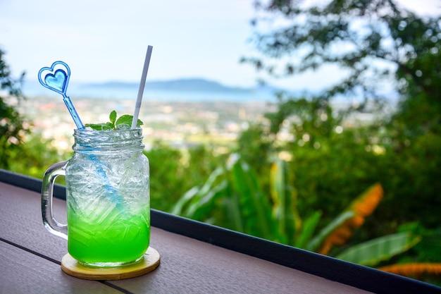 Refresco italiano de manzana con hoja de menta sobre una mesa de madera con fondo natural borroso