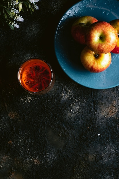 Refresco de manzana roja sobre una mesa oscura con manzanas