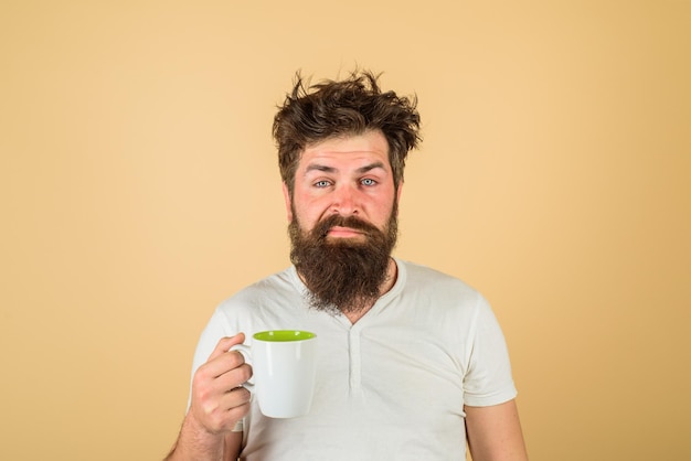 Refresco matinal e bebida conceito de café da manhã homem barbudo com xícara de café branco cansado homem sonolento