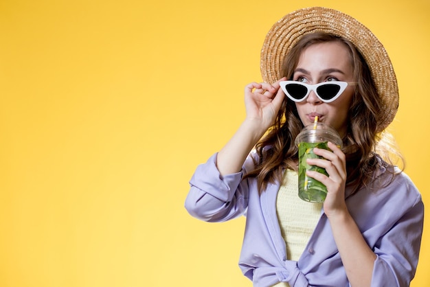 Refresco de verano Bebida fría Mujer feliz con gafas de sol sosteniendo un vaso de plástico de mojito Bebida no alcohólica Limonada de desintoxicación