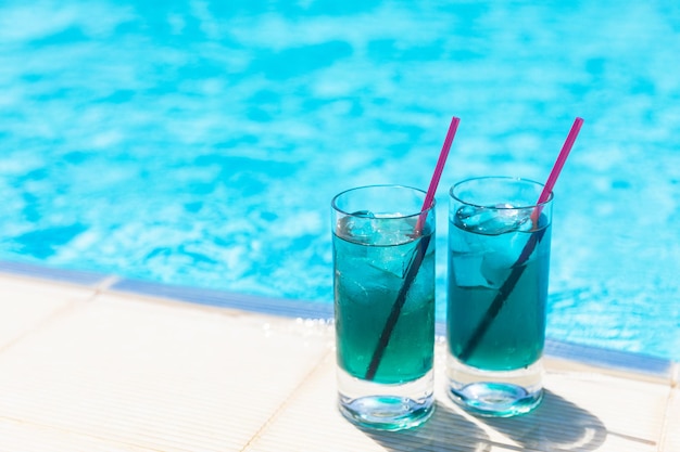 Refrescos fríos cócteles azules con hielo cerca de la piscina en un día soleado