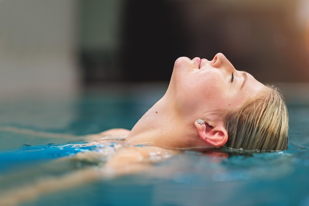 Refresque el cuerpo, calme la mente Captura de una mujer joven relajándose en la piscina de un spa