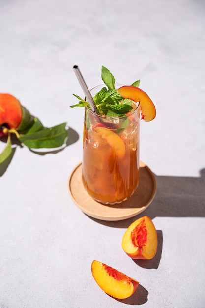 Refrigerante chá de pêssego com gelo e hortelã Bebida fria de verão caseira em um fundo claro com frutas frescas e sombras Vista superior