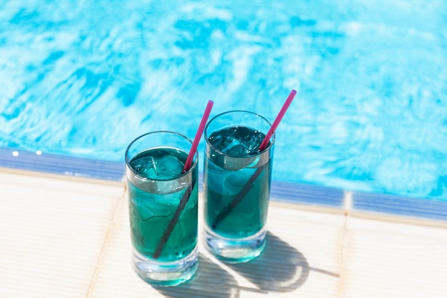 Foto refrigerantes refrigerados dois coquetéis azuis com gelo perto da piscina em dia ensolarado