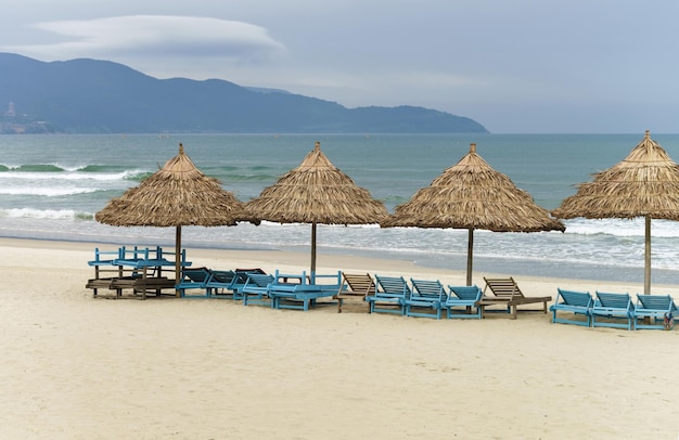 Refugios de palmeras y tumbonas en China Beach en Da Nang, en Vietnam. También se la llama Playa Non Nuoc. Mar de China Meridional y Montañas de Mármol en el fondo.