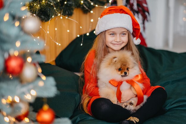 Un regalo de bienvenida para Navidad un cachorro de Pomerania. Una linda niña recibió un perrito como regalo de Navidad. La alegría del regalo. Niño feliz.