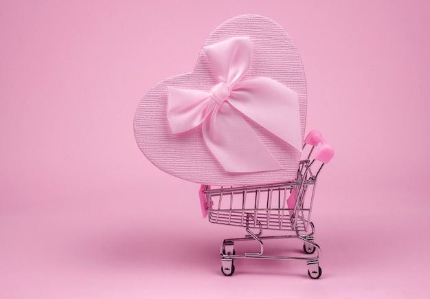 Regalo de corazón rosa con lazo para el día de San Valentín en euroconector de compras sobre un fondo rosa, regalo de entrega