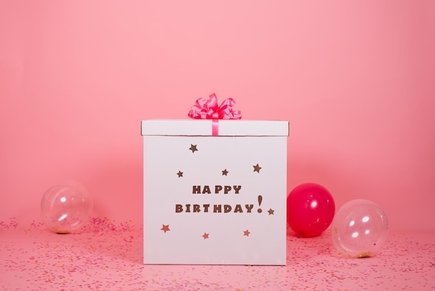 Regalo de cumpleaños de caja de regalo grande con lazo rojo con globos al lado del fondo