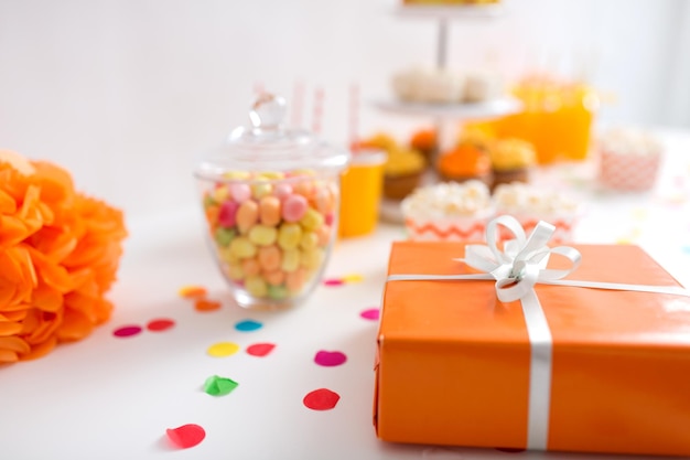 regalo de cumpleaños en envoltura naranja en la mesa en la fiesta