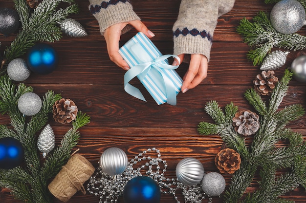 Regalo decorado con cinta rodeada de adornos navideños en mesa de madera