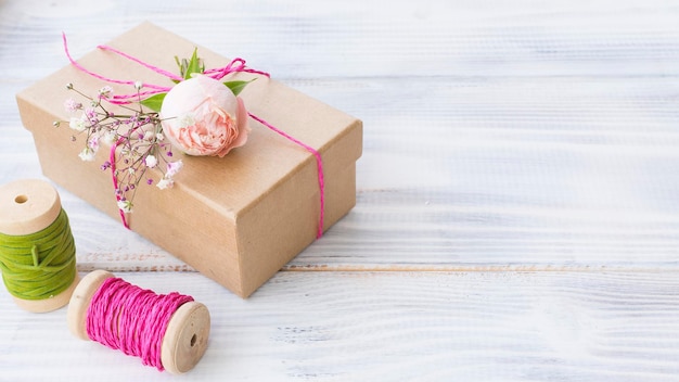 Regalo envuelto en una caja La caja está decorada con una delicada rosa fresca y una ramita de gypsophila