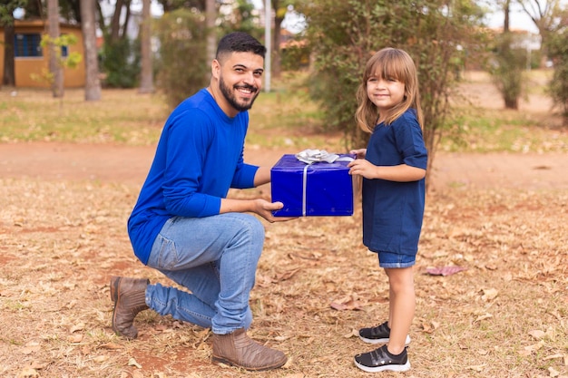 Este regalo es para ti papá La niña entrega el regalo del día del padre al padre en el parque