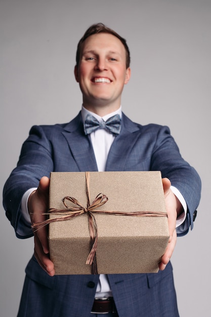 Este regalo es para ti Parte del hombre en traje que muestra la caja de regalo con una sonrisa mientras está de pie