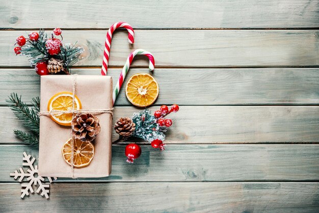 Regalo de Navidad con bastones de caramelo conos de pino y rodajas de naranja secas sobre fondo de madera