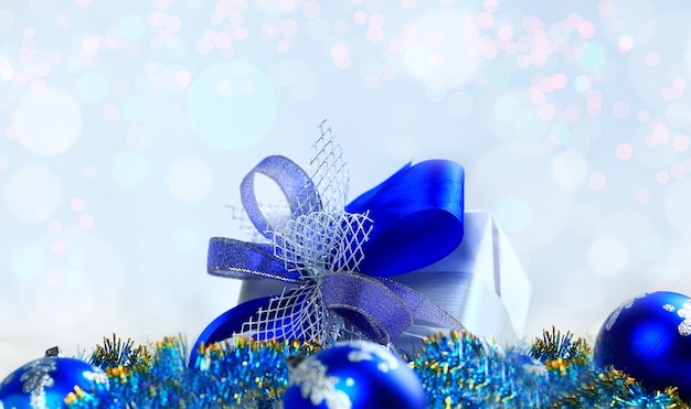 Regalo de Navidad y bolas azules sobre fondo blanco.