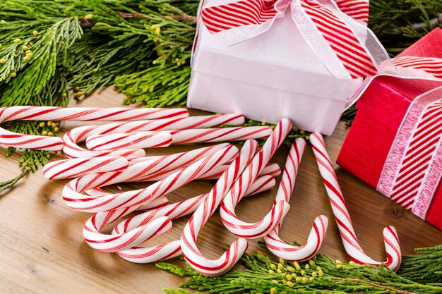 Regalo de Navidad en caja blanca sobre mesa de madera con ramas de hoja perenne en vivo.