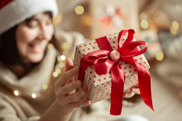 Regalo de Navidad de cerca en manos femeninas en una pared borrosa. Concepto de regalar un regalo.