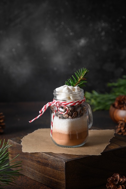 Regalo de Navidad comestible casero en tarro de masón para bebida de chocolate sobre fondo oscuro. De cerca. Delicias festivas de Navidad. Formato vertical.