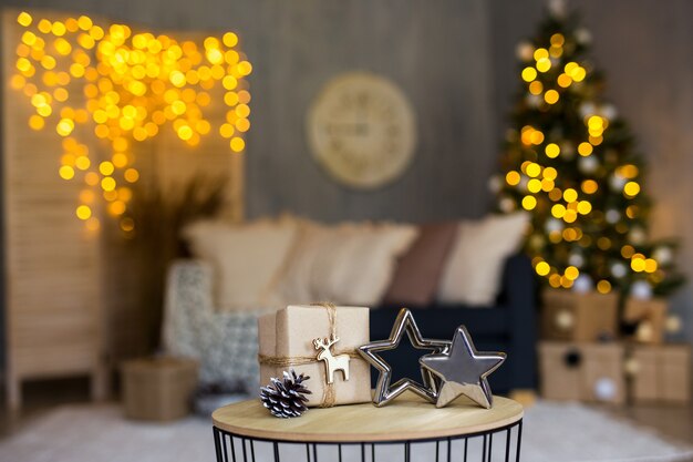 Regalo de Navidad envuelto y estrellas en salón decorado con árbol de Navidad