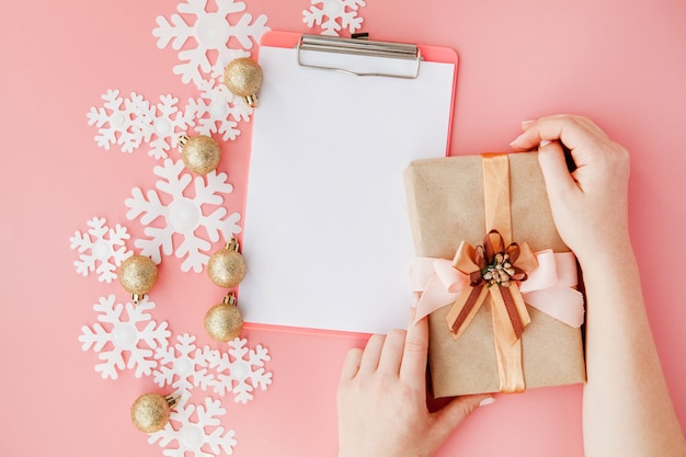 Regalo de Navidad en manos de mujeres y cuaderno, una vista desde arriba