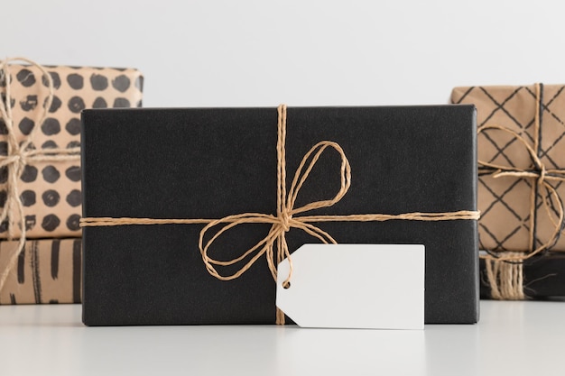 Regalo de navidad negro con maqueta de etiqueta en blanco con múltiples regalos de navidad en una mesa blanca