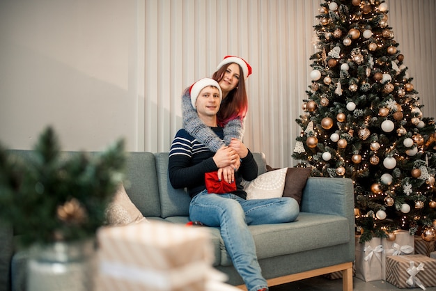 Regalo de Navidad. Pareja feliz con sombrero de Santa con regalo de Navidad y año nuevo en casa.