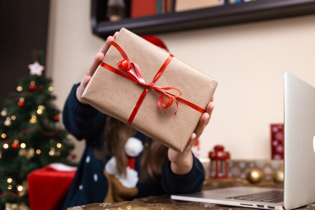 Un regalo de Navidad. Retrato de mujer sin rostro con caja de regalo con cinta roja sobre un fondo de Navidad. Concepto de vacaciones de año nuevo