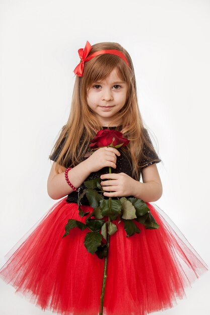 Un regalo para los seres queridos. Niña con una rosa en sus manos, aislada.